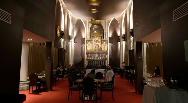 Varios huéspedes desayunan frente a un altar reutilizado en el ahora hotel Martin's Patershof, en el centro de Malinas, Bélgica, el lunes 19 de junio de 2023. 